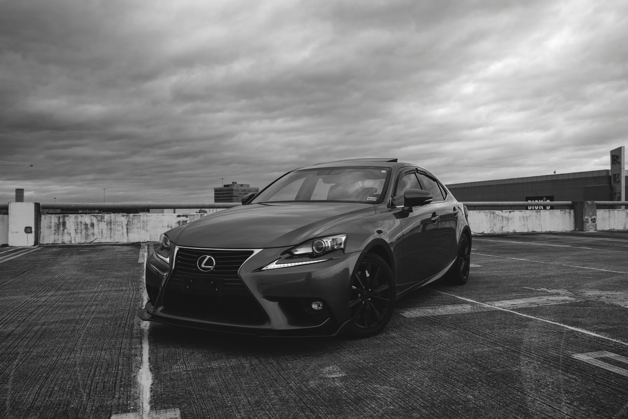 Lexus IS F-Sport parked on a rooftop car park under a heavy sky